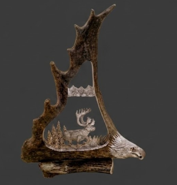 Decorative piece out of a a caribou antler.  Hand carved insert featuring a caribou and mountain landscape on a dark background with an eagles head at the base.