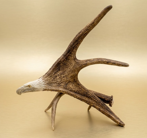 Antler with eagle sculpture on a beige background