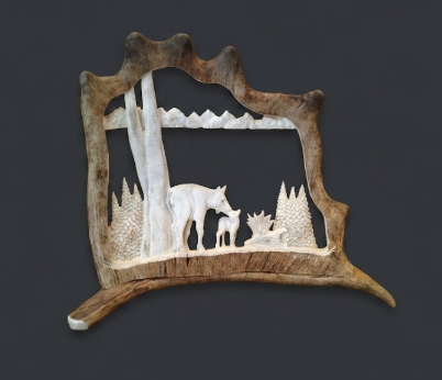 Decorative wall art with hand cut cut- design of a wolf and mountains on a caribou antler frame.