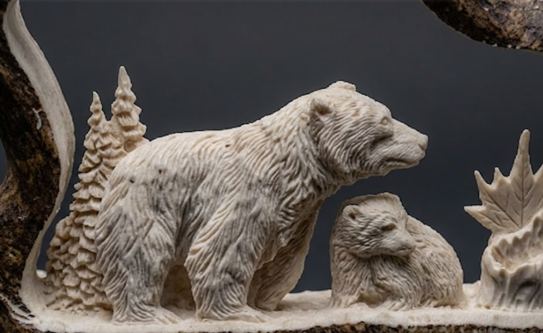 Carved antler sculpture of a bear and cub with a forest background