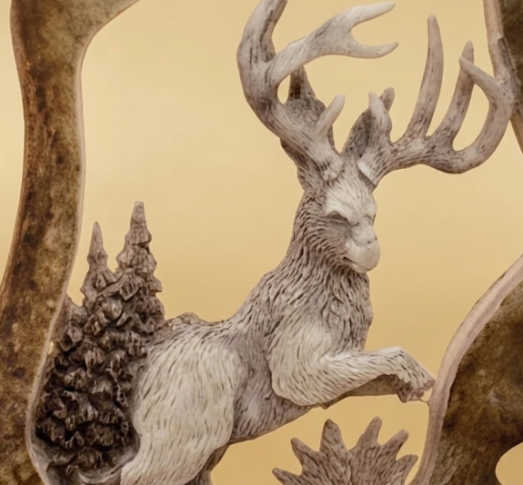 Decorative up close art of a jackalope carved in a  caribou antler and trees on a beige background