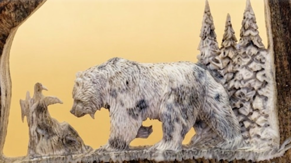 Close up of a carved bear in a natural setting with trees and rocks on a yellow background