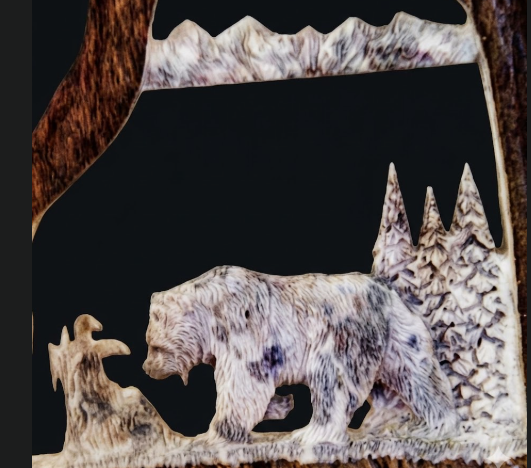 Carved antler bear scene with mountains and trees
