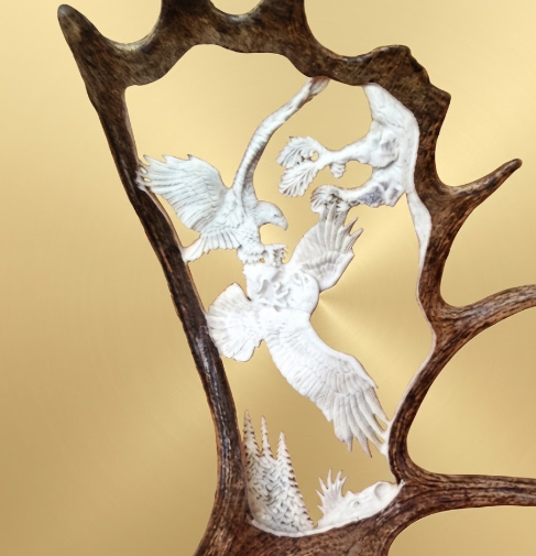 Hand carved Moose antler depicting two eagles fighting in the mountains.