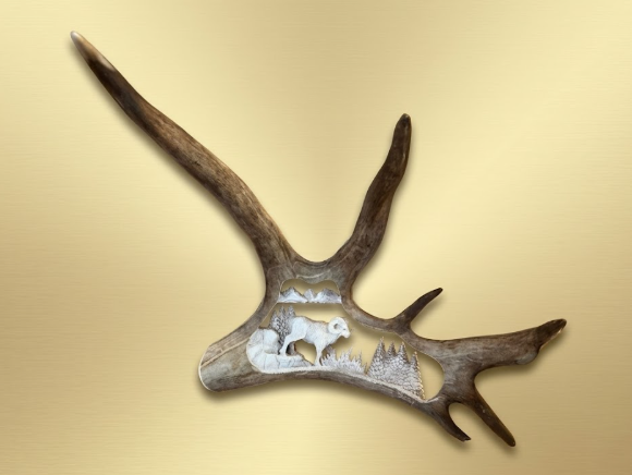 Decorative hand carved antler with cut-out designs on a beige background