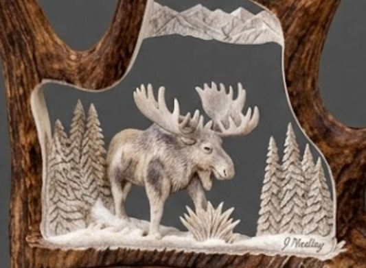 Decorative wall art  or table art with a moose and forest design on a wooden stand.