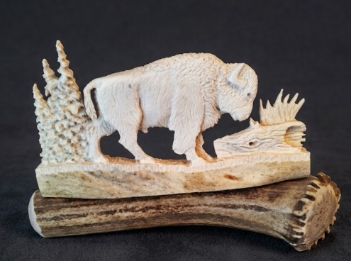 Carved antler buffalo figure on a dark background