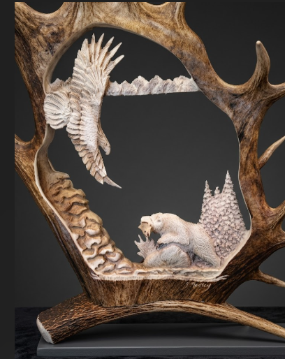 Caribou antler carved scene of a bear and eagle on a dark background
