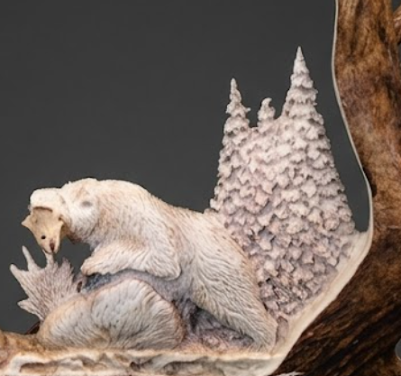 Carved antler scene of a bear catching a salmon with a forest background