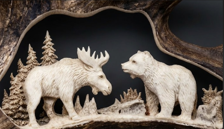 Carved scene of a moose and bear with trees and mountains in the background.