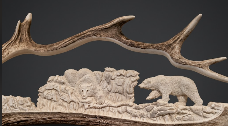 Carved antler with bear and cub design on a dark background