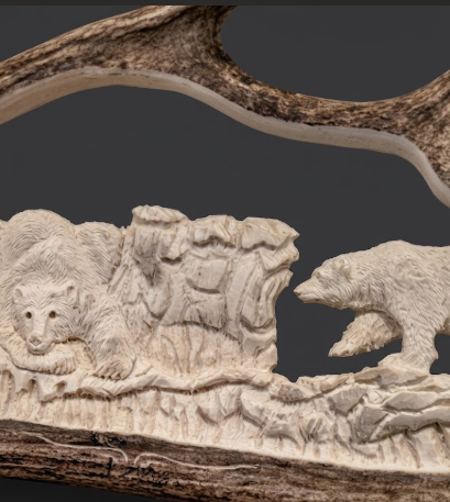 Carved antler with bear and cub design on a dark background