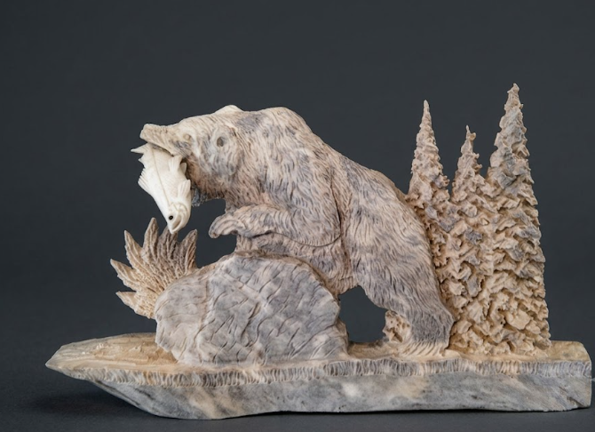 Carved stone bear sculpture with trees on a dark background