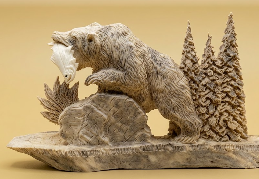 Carved stone bear sculpture with trees on a beige background