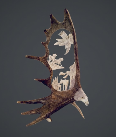 Decorative Carved moose antler  with carvings of animals on a dark background