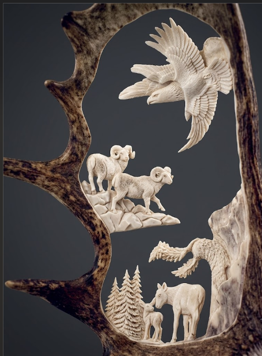Carved moose antler with detailed animal figures on a dark background