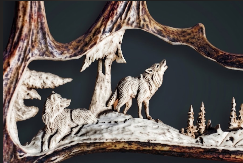 Decorative wolf antler carving of wolves on a branch with a dark background