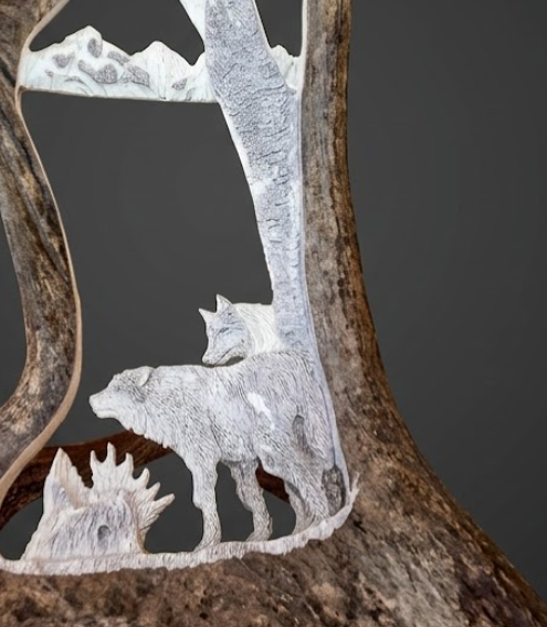 Carved wooden scene with two wolves and a tree on a dark background