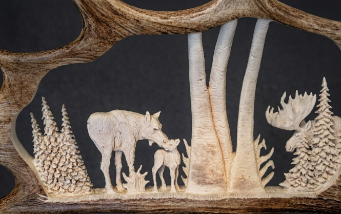 Carved wooden scene with animals and trees on a dark background