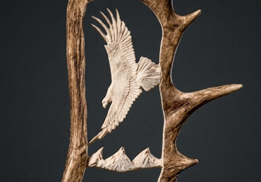 Carved eagle on a deer antler against a dark background