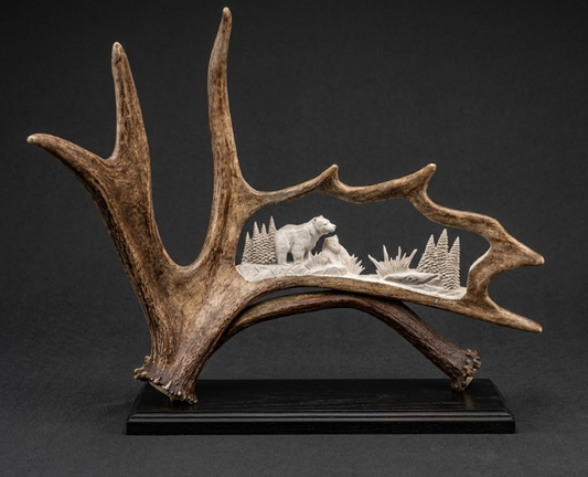 Decorative antler with a carved bear and landscape on a black background