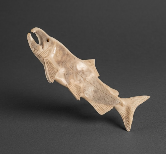 Carved stone fish figure on a dark gray background