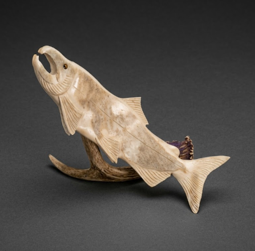 Carved stone fish sculpture on a dark gray background