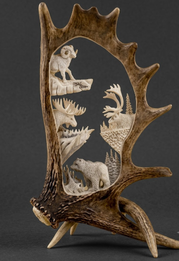 Carved antler with animal figures on a dark background