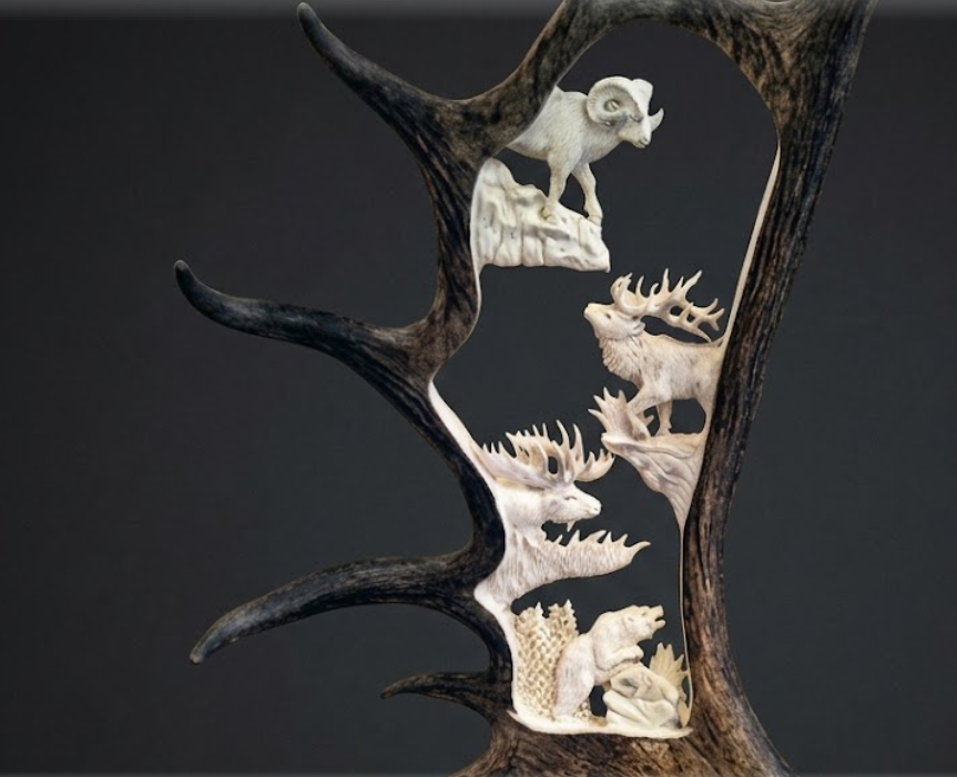Decorative wall moose antler art with animal carvings on a dark background