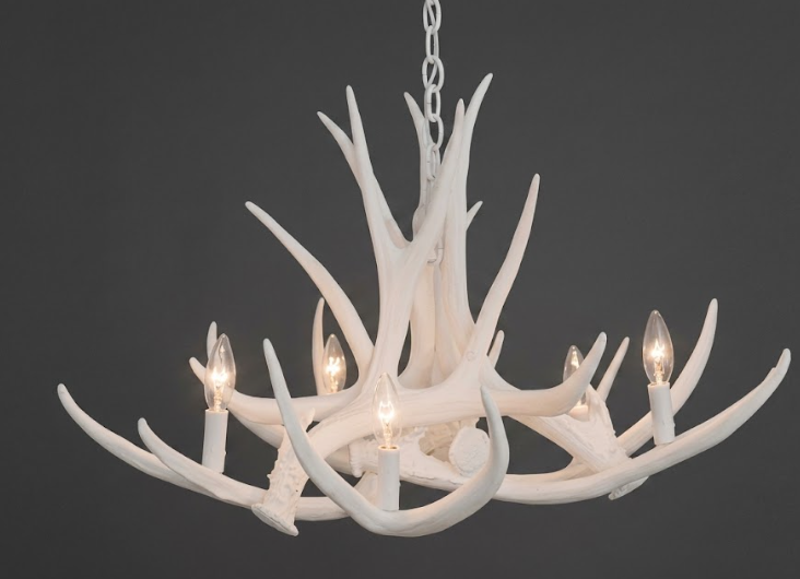 White faux deer antler chandelier with six lights on a dark background