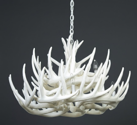 White faux deer antler chandelier against a dark background