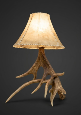 Table lamp with antler base and beige lampshade on a dark background