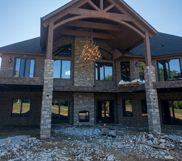 Large two-story house under construction with visible foundation and materials and a faux elk antler chandelier hanging