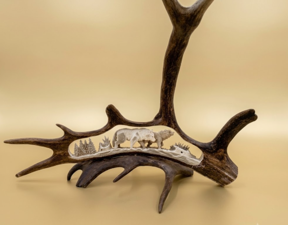 Carved  antler with two wolves and a tree on a beige background