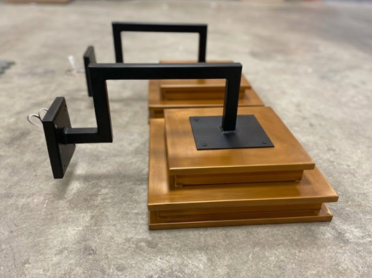 Wooden platform with black metal copper wall sconce brackets on a concrete floor