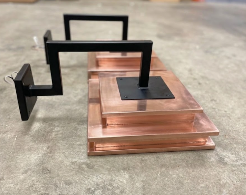 Copper wall sconce and black metal stand on a concrete floor