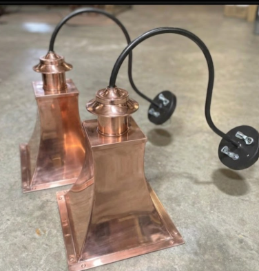 Copper wall sconce lamp with a black cord on a concrete floor