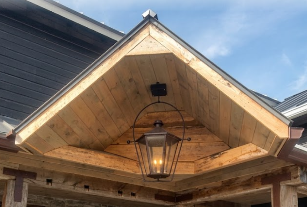 Foyer entry way dark copper outdoor pendant light near a wood wall and wood posts and a wood entry way door