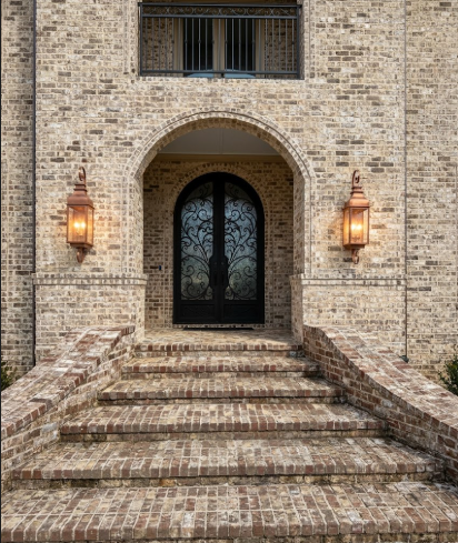 2 copper outdoor gas lanterns foyer entryway light on a dark brick wall and a glass door 
