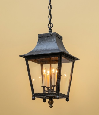 Decorative hanging Decorative outdoor entryway kitchen island pendant foyer light hanging against a stone wall. lantern with glass panels on a beige background