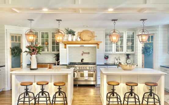 Modern kitchen with 4 kitchen island pendant lights and white cabinets, stainless steel appliances, and wooden countertops.