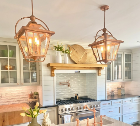 Kitchen with hanging kitchen island pendant lights, stove, and cabinets.
