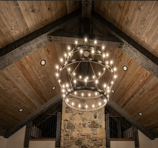  3 tier foyer entryway pendant light chandelier hanging from a wood ceiling with a rock wall and staircase in the background