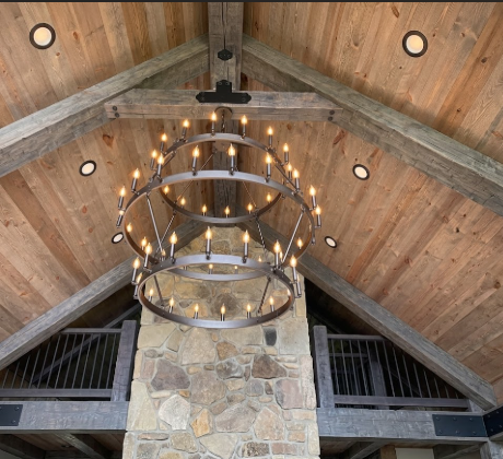 Large  3 tier foyer entryway pendant light chandelier hanging from a wood ceiling with a rock wall