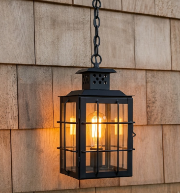 Black Copper foyer entryway pendant light with a lit bulb with glass panels on a dark background hanging on a wooden wall
