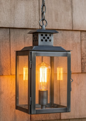 Vintage-style Copper foyer entryway pendant light with a lit bulb with glass panels on wooden wall