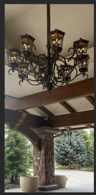 Decorative entryway foyer lights copper chandeliers hanging from a ceiling with a stone building and trees in the background