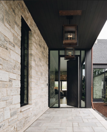 Modern house exterior with stone wall, glass door, and entryway pendant lights.