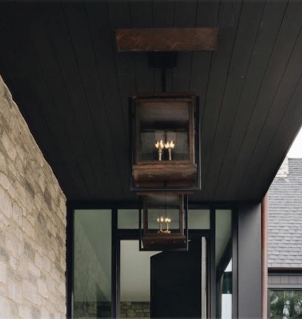 Decorative ceiling foyer entryway pendant lights in a modern interior setting with stone wall and glass door.