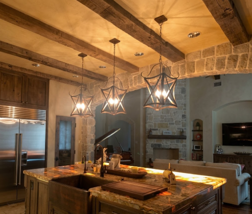 Copper foyer or entryway kitchen island pendant light or chandeliers hanging above a kitchen island with marble, wood beams and rock 